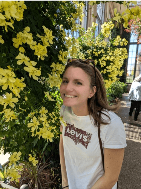 Molly standing next to yellow flowers and smiling.